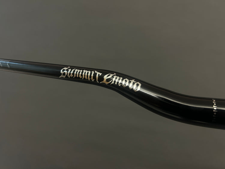 Close-up of the Summit Emoto logo on gloss black 31.8mm handlebars